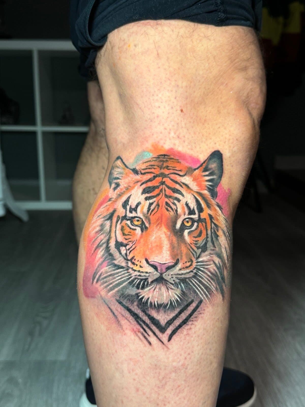 Tatuaje a color de la cabeza de un tigre sobre un fondo de acuarela