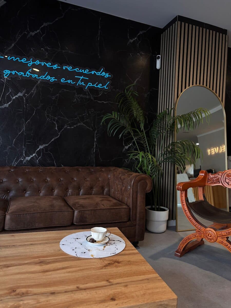 Salón del estudio Velvet con sofá, espejo y pared de mármol negro